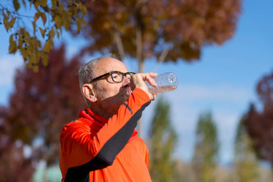 Man with glasses drinking a bottle of water during a run
